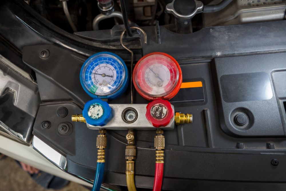Automotive air conditioning pressure gauges with blue and red dials, used for AC repair and maintenance.