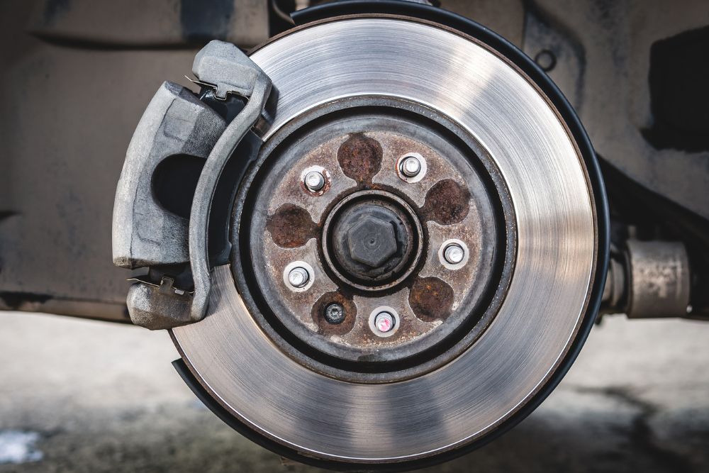 Close-up of a vehicle brake system, featuring a brake caliper and rotor, emphasizing the importance of proper brake maintenance for vehicle safety and performance.